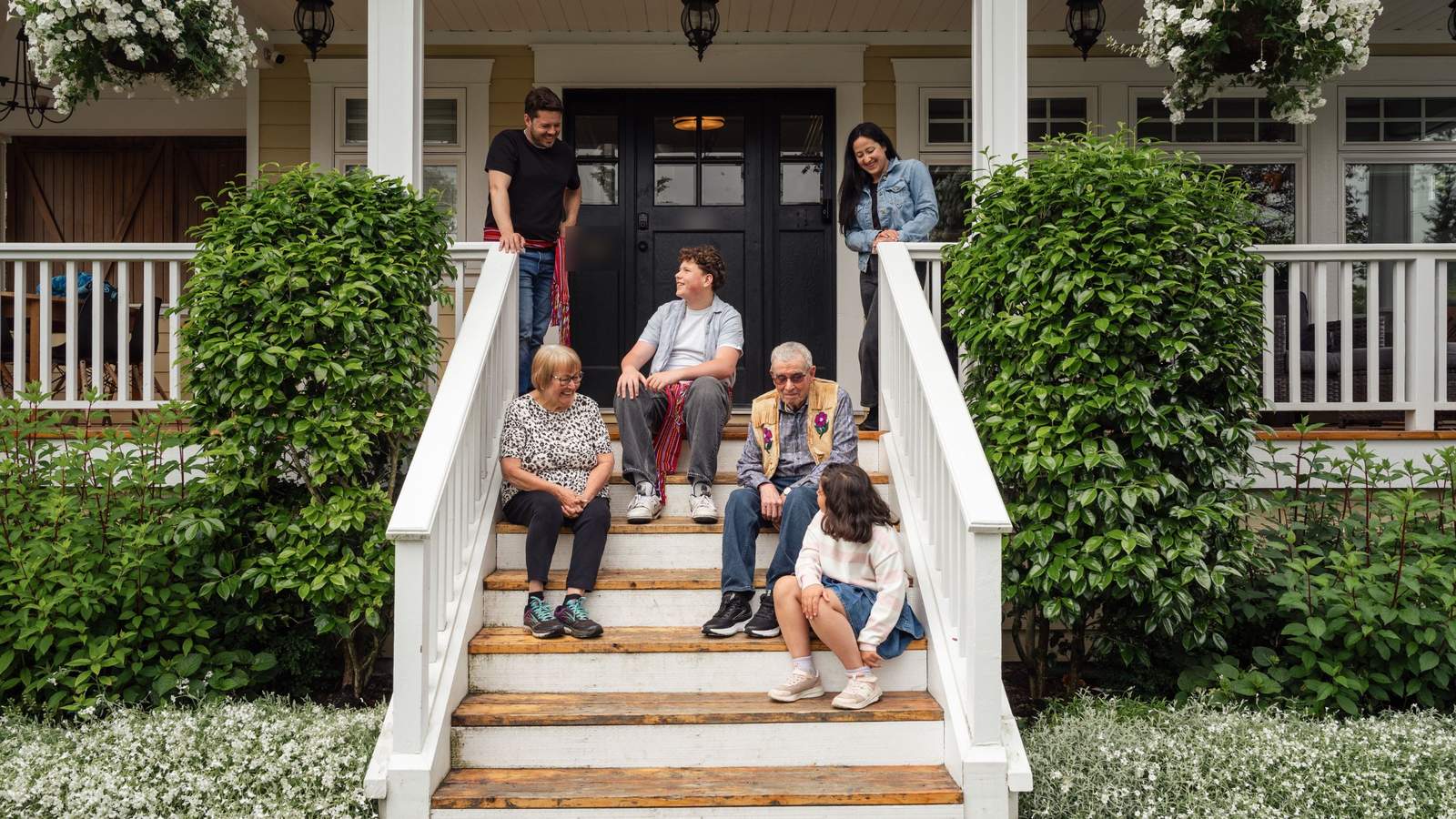 A family sitting together on the front steps of their home