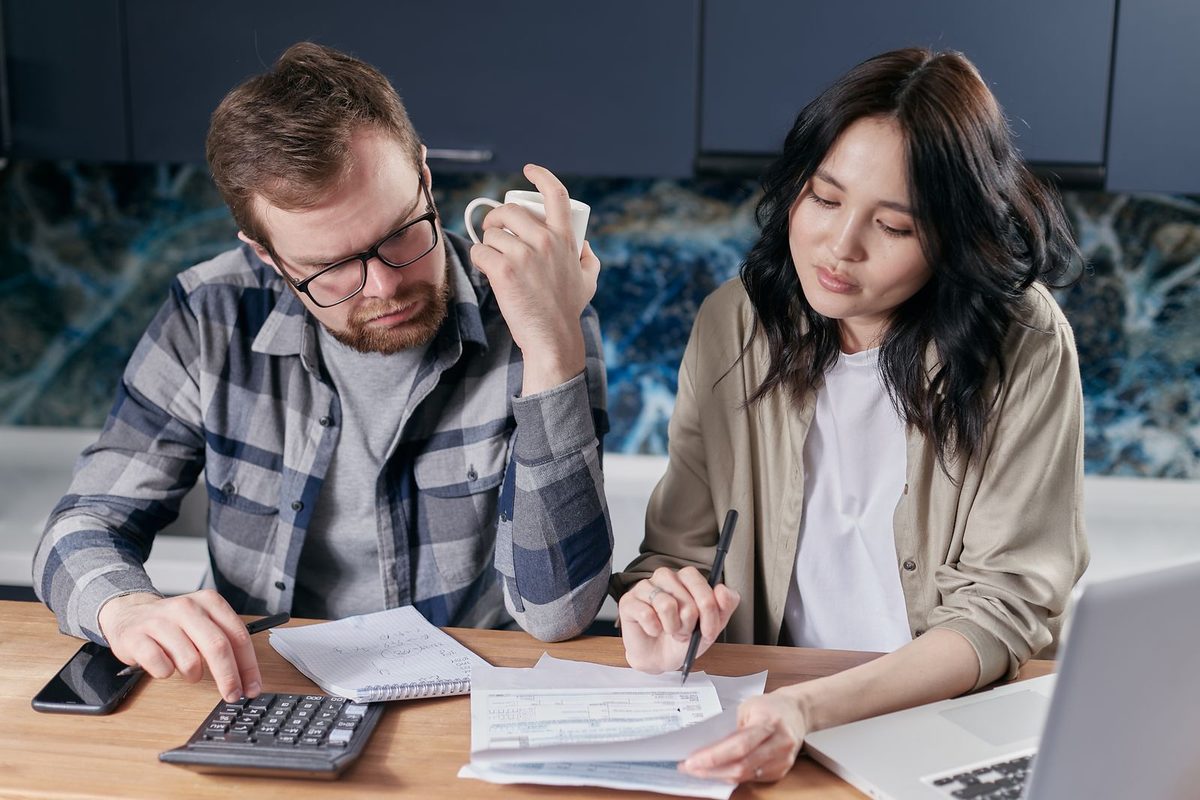 A couple working out their budget with a calculator and a laptop