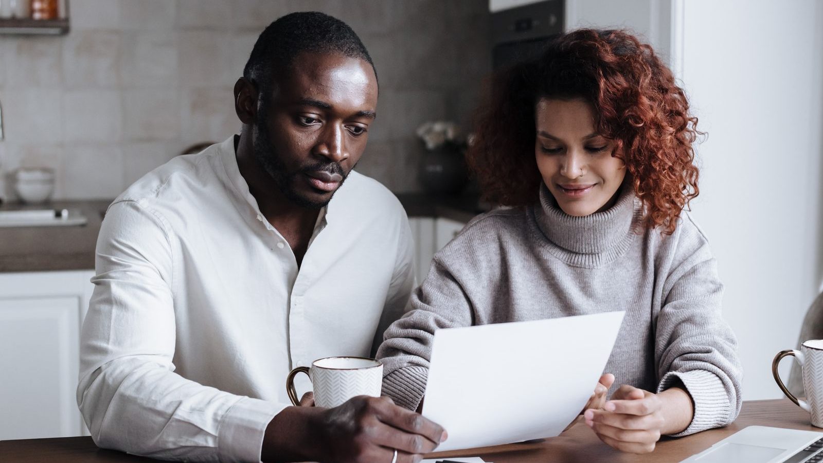 A couple reading through paperwork together at a kitchen table