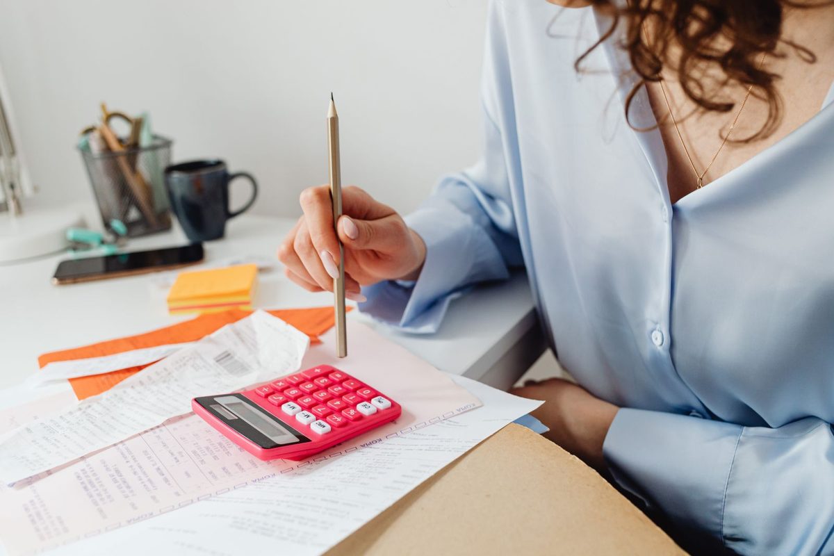 A woman working through bills with a calculator and a pencil
