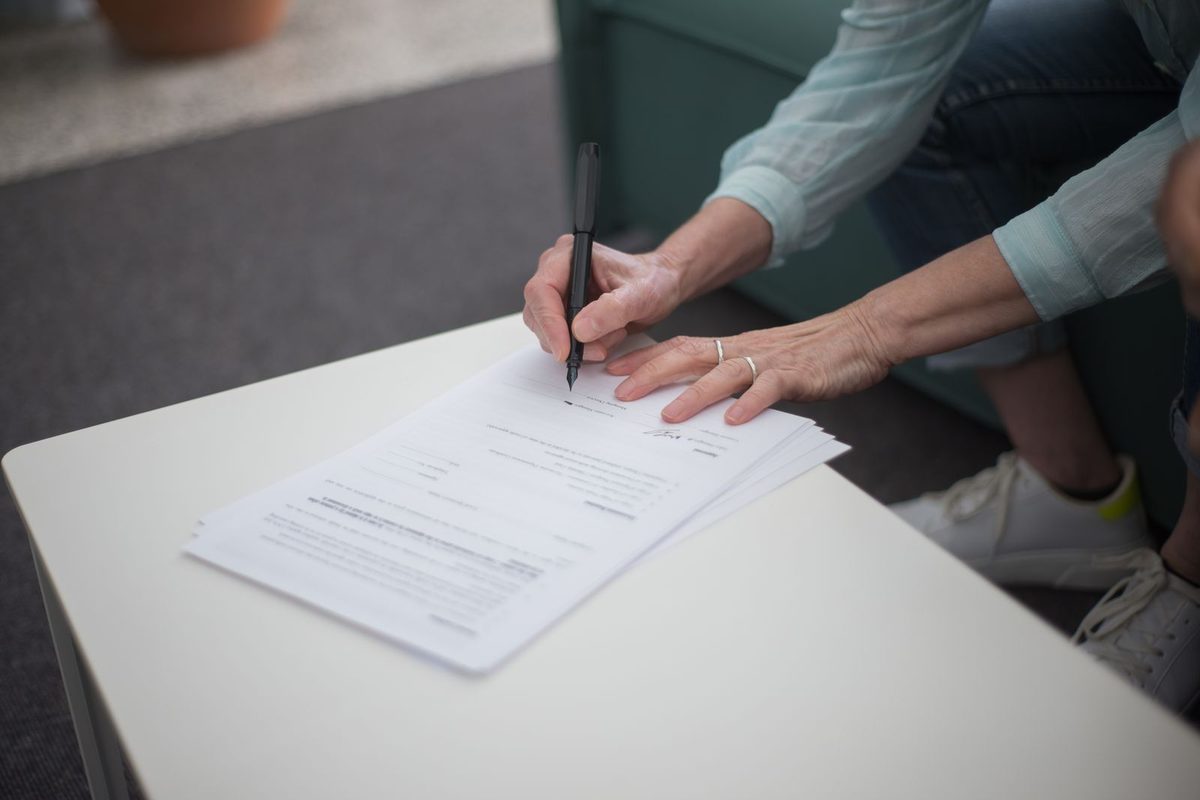 A person signing documents at a table
