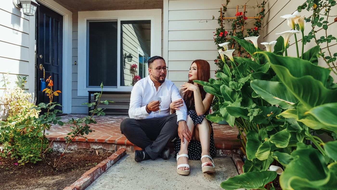 A couple sitting together on the front steps of their home