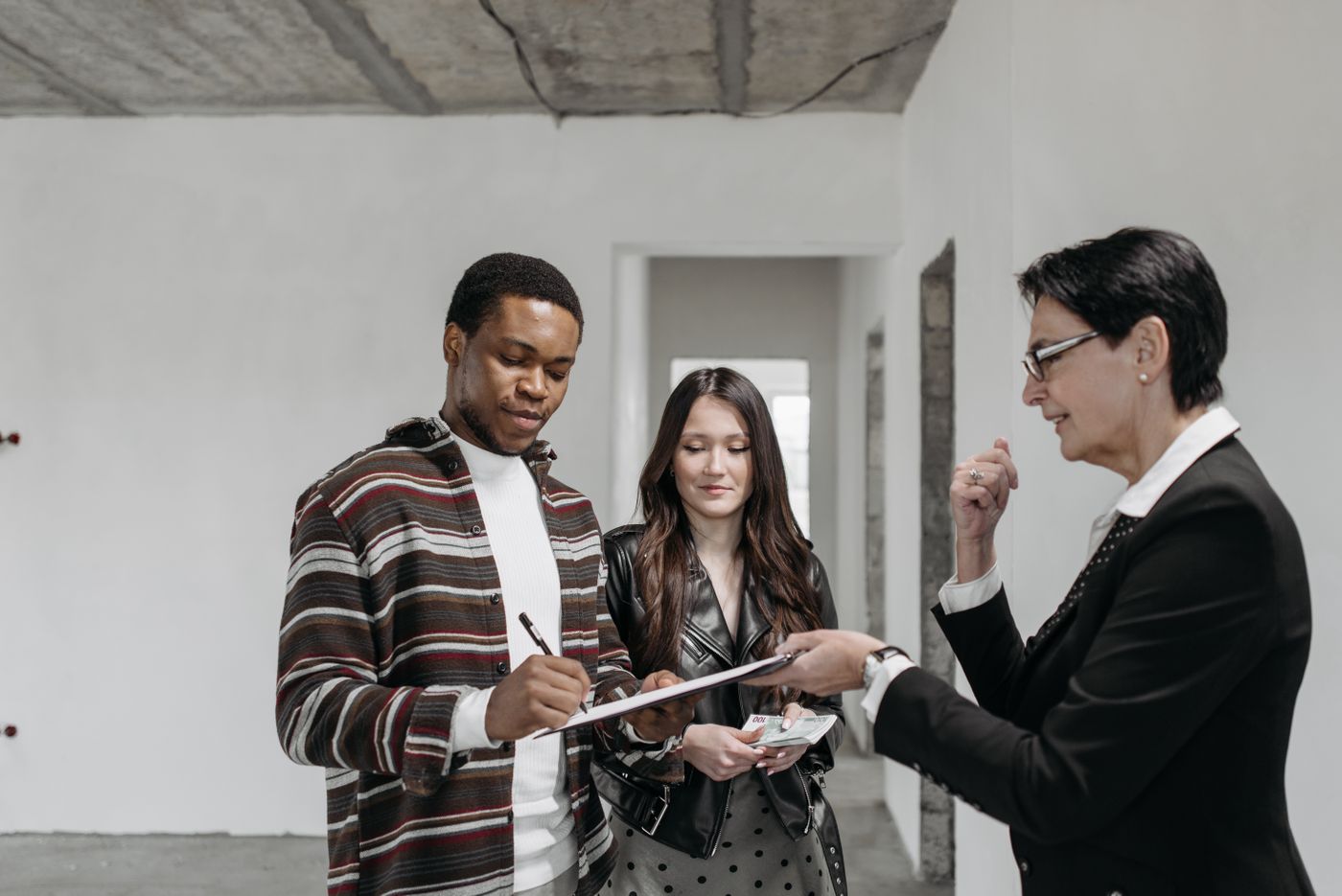 A couple signing closing documents with a closing agent