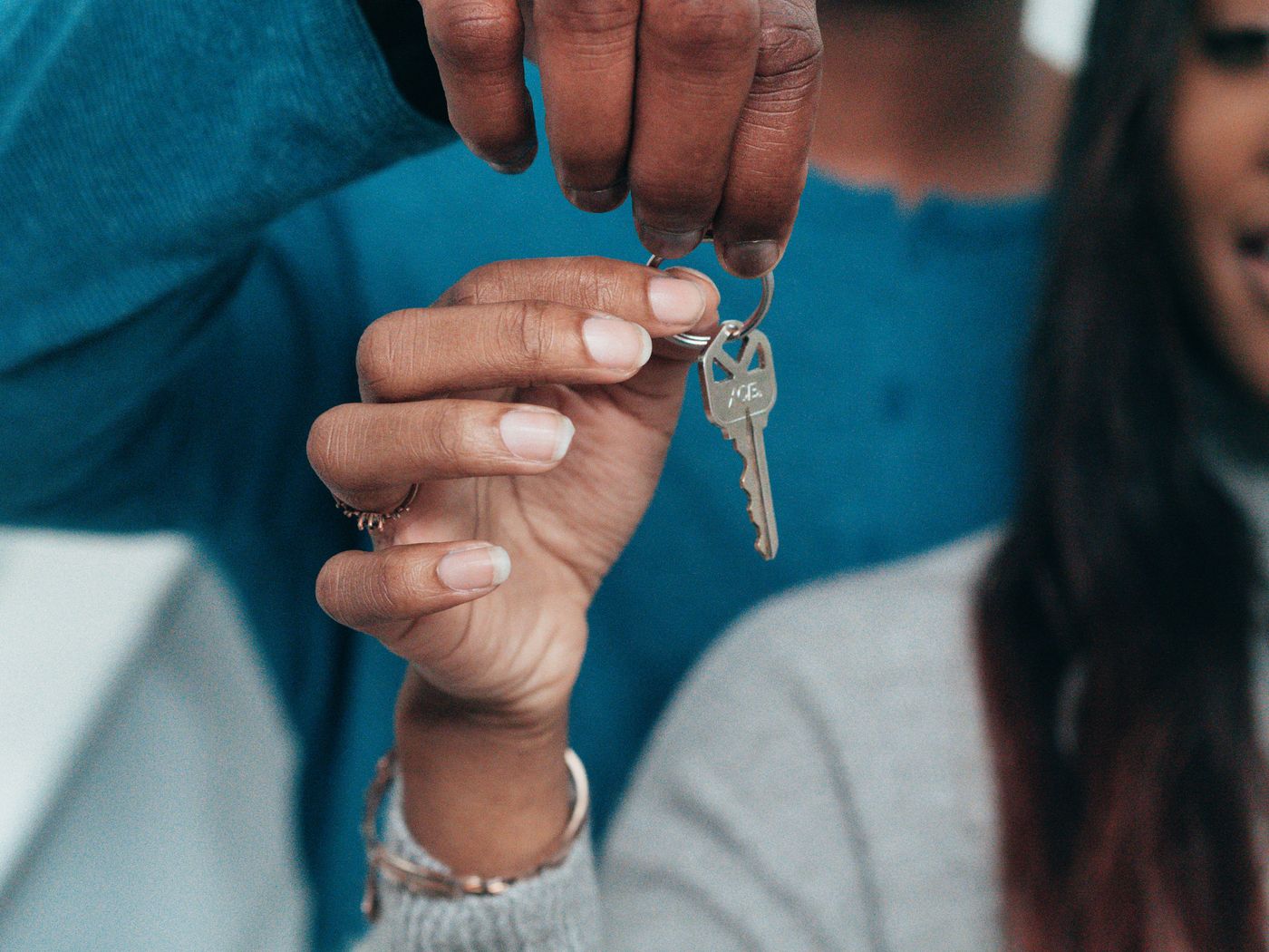 Hands passing a house key to a new owner